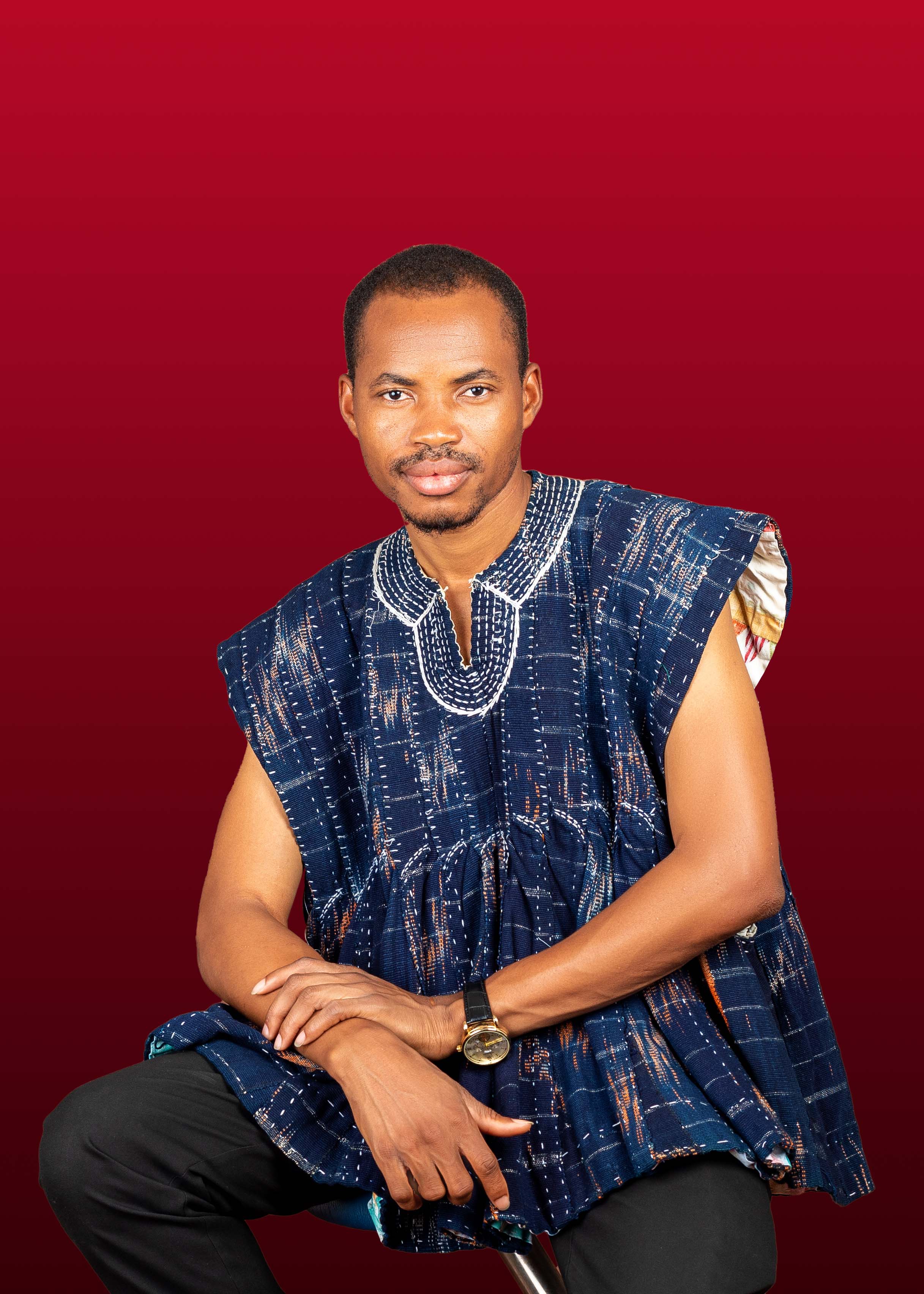 Matthew Nyaaba posing in front of a red background.
