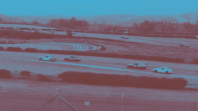 Race cars speed around a track.